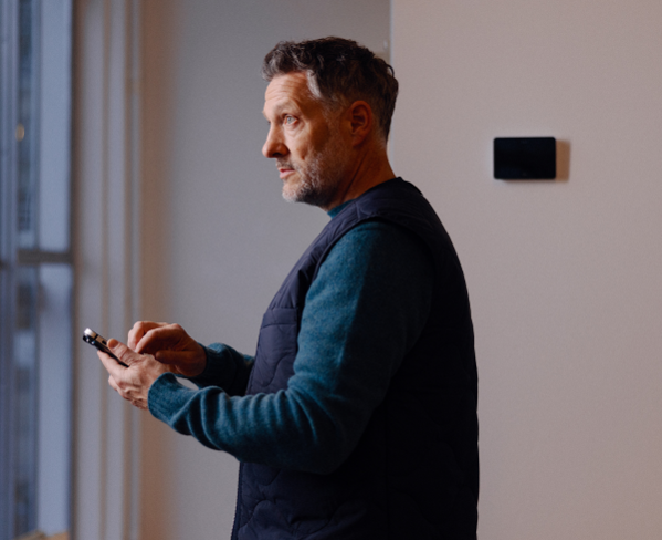 Building manager adjusting indoor climate settings of office building on his smart phone near large windows.