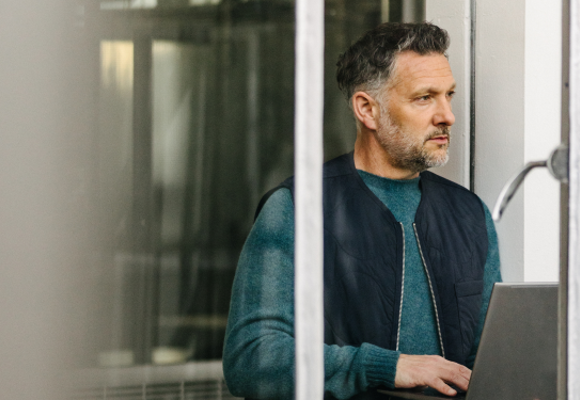 Facility manager managing the building with digital smart tools on laptop, looking out window